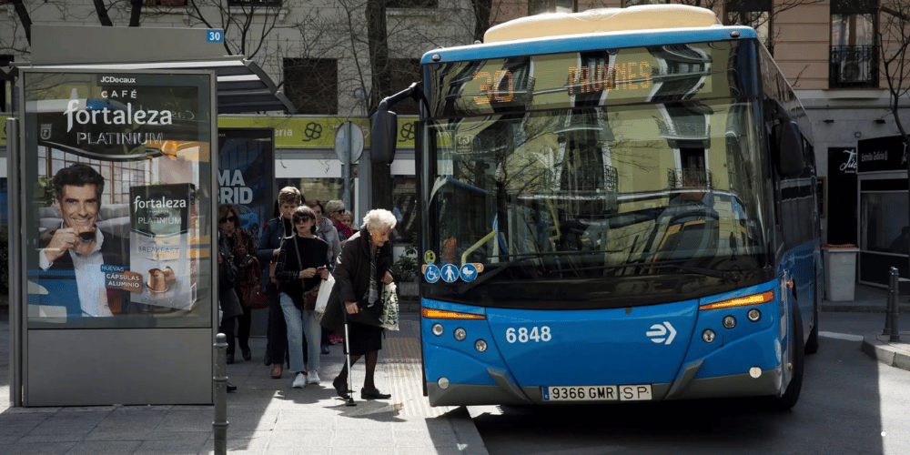 Autobús de la EMT Madrid estacionado, anunciando los días de transporte gratuito en Madrid.